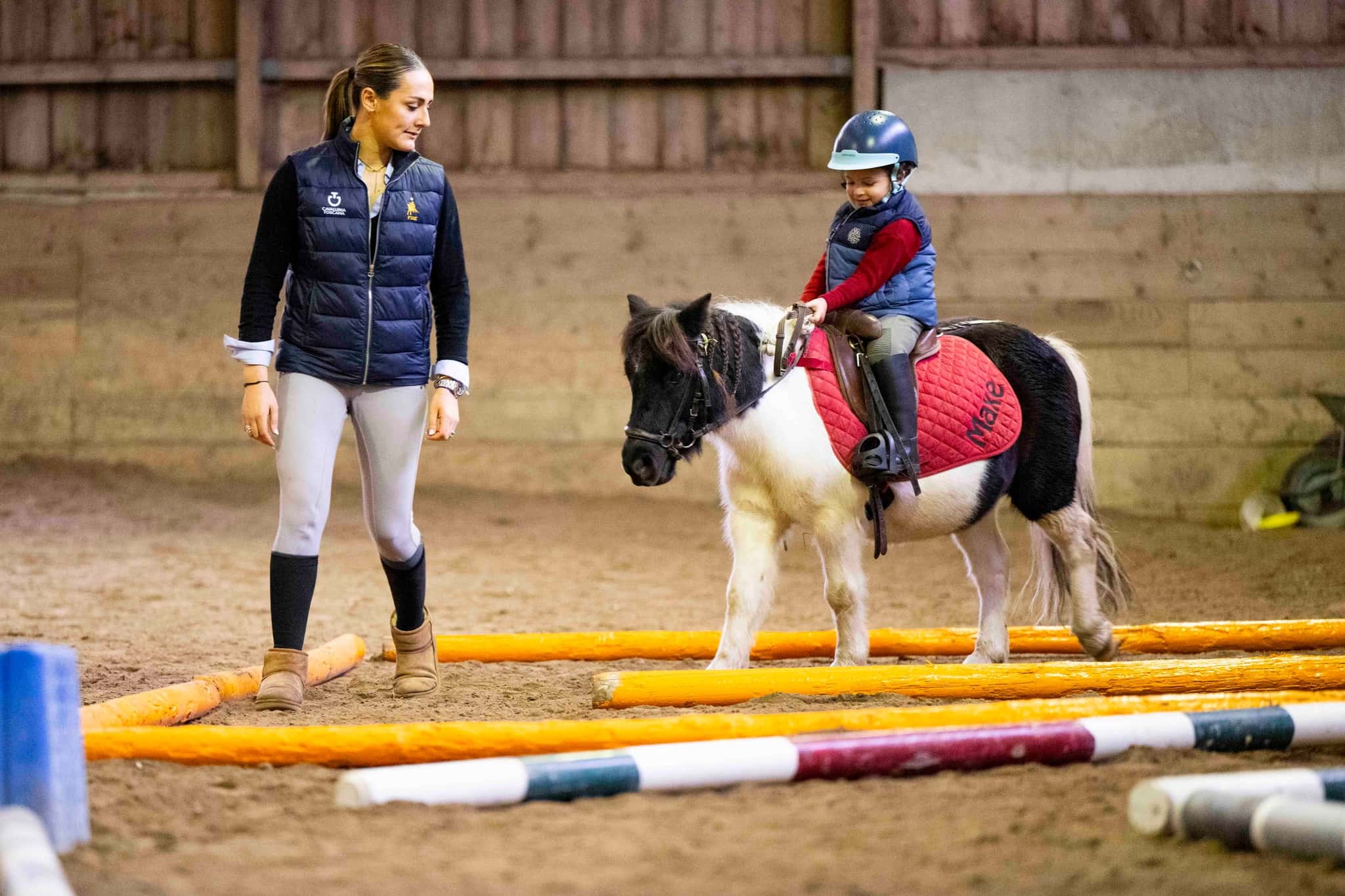 Cours de poney dans le manège, enfant sur poney avec instructeur